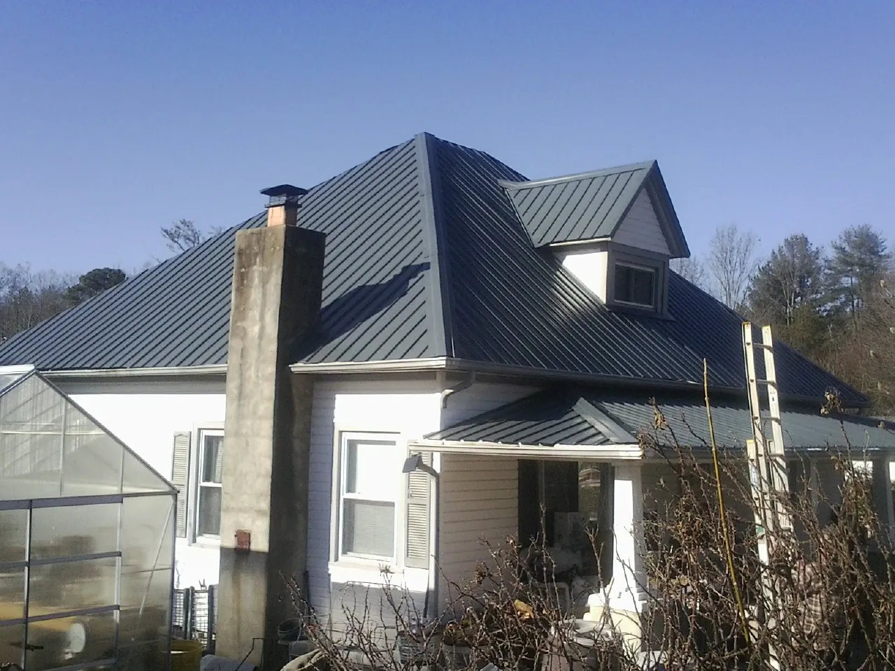 Dark blue standing seam metal roof on a white farmhouse with dormer — Slate & Tile Roof Repair by Roofing Brothers in Pavilion