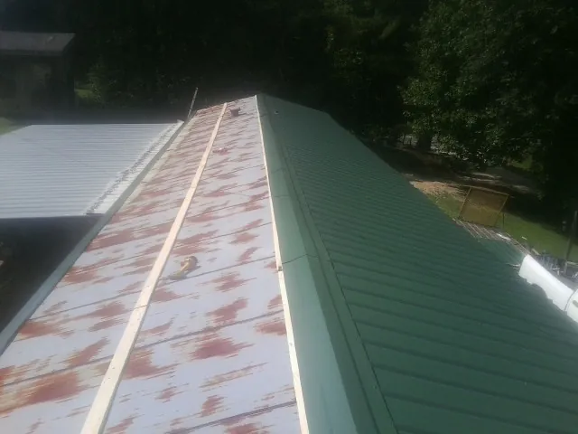 Old rusted panels beside newly installed green metal roofing — Wind Damage Roof Repair by Roofing Brothers in Pavilion