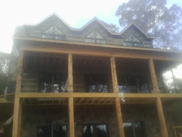 Dormers and porch framing on a large log home under construction — Roof Coating work by our crew in Pavilion
