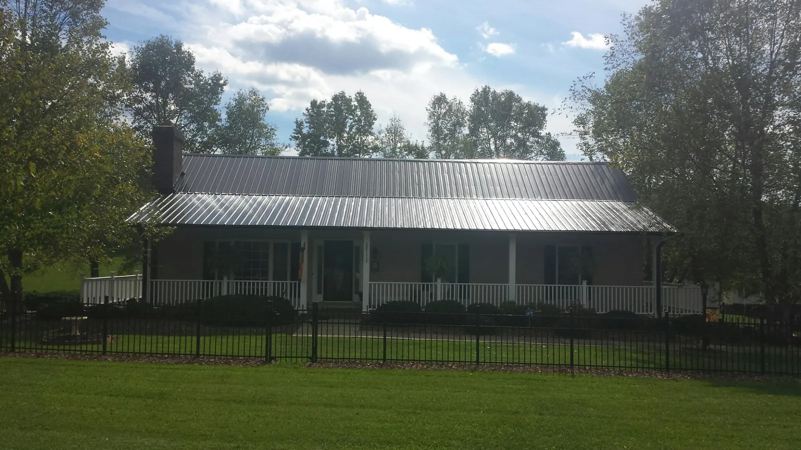 Gray metal roof on a brick ranch with a full width front porch — Gutter Guard Installation work by our crew in Pavilion