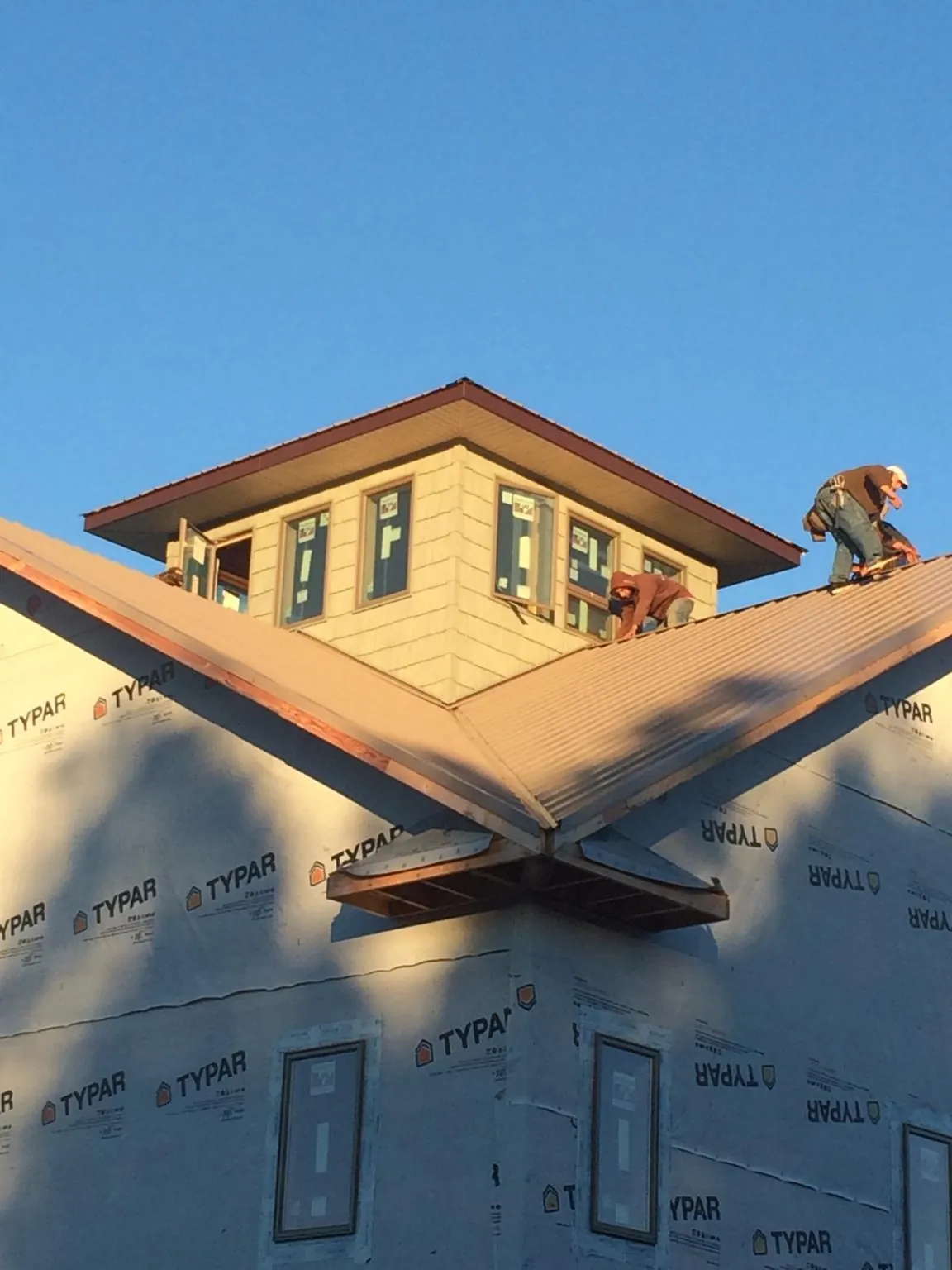 Roofers working around a rooftop cupola on a new metal roof at sunset — Roof Waterproofing in Pavilion by Roofing Brothers